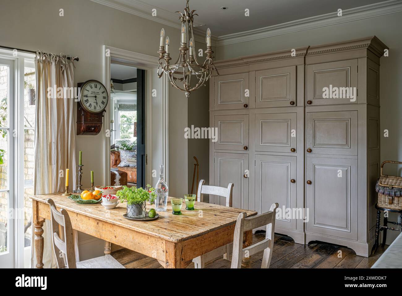 Cucina in agriturismo con orologio a parete e grandi armadi a Wimbledon home, Londra sud-occidentale, Inghilterra, Regno Unito. Foto Stock