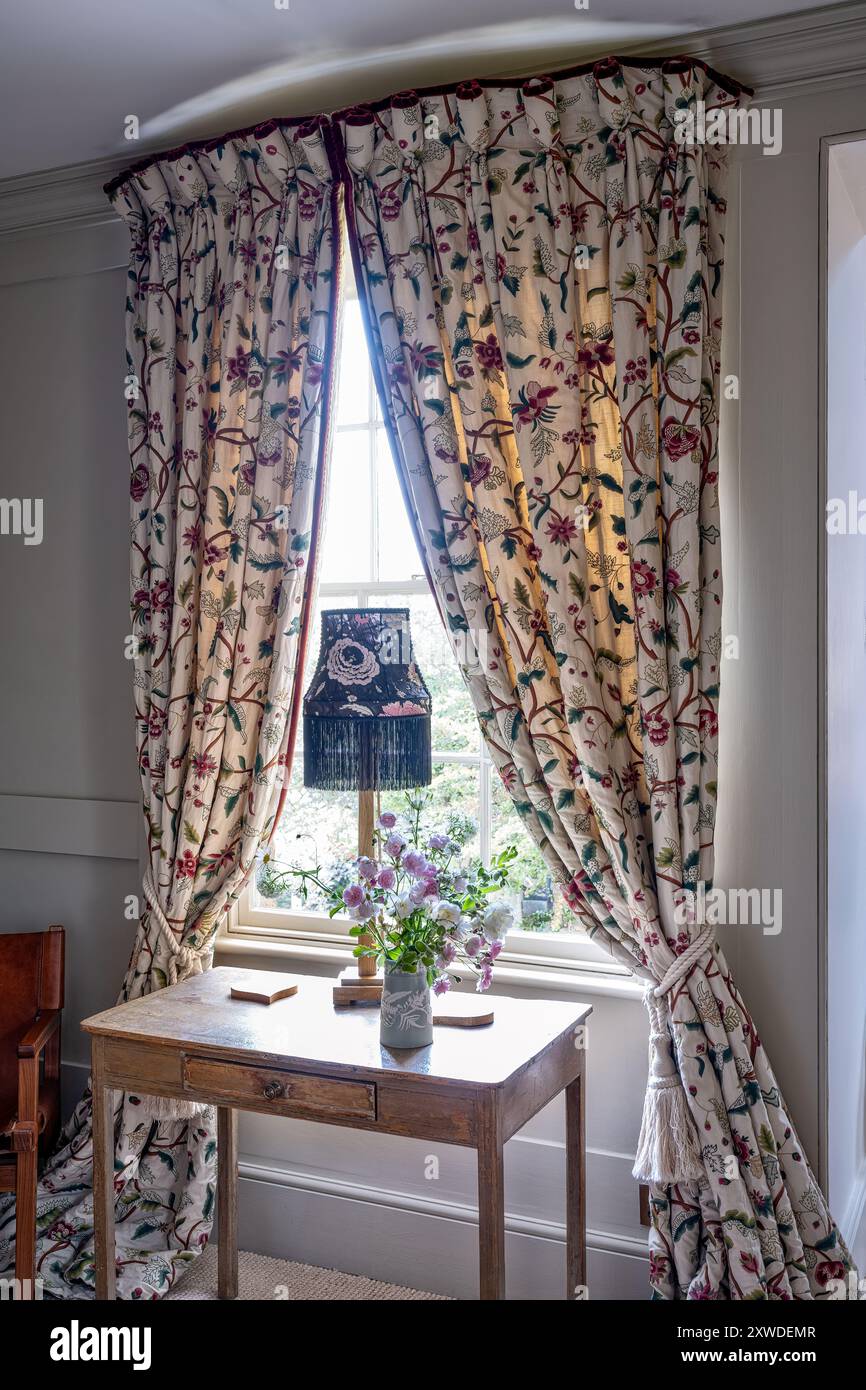 Lampada d'epoca sul tavolo in finestra con tende floreali nella casa di Wimbledon, a sud-ovest di Londra, Inghilterra, Regno Unito. Foto Stock