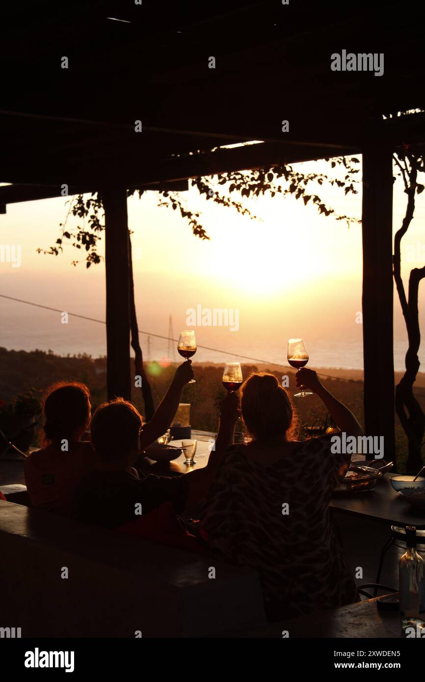 Sagome di persone che bevono vino nella luce dorata del tramonto. Foto Stock