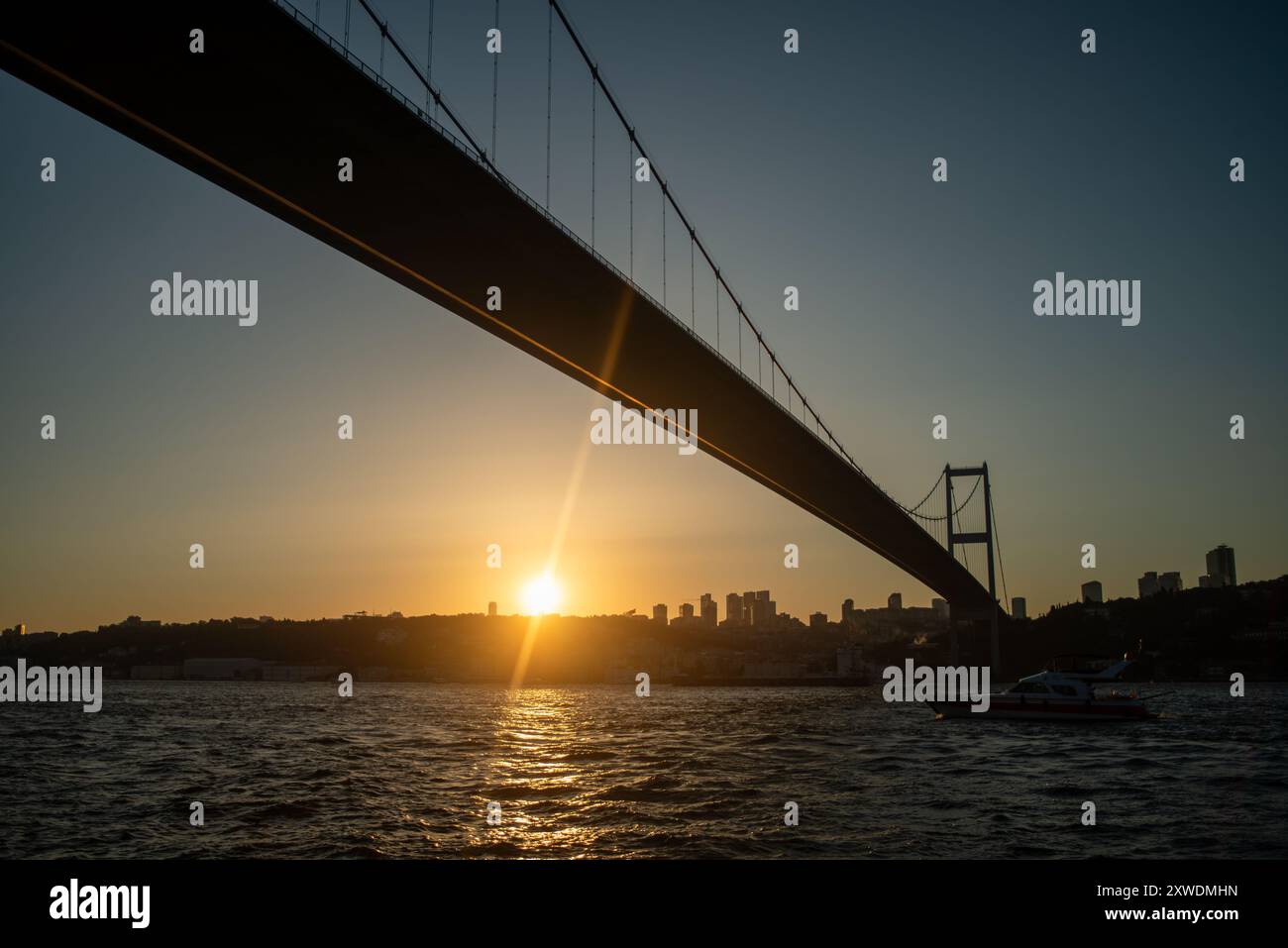 Una vista mozzafiato del Ponte sul Bosforo di Istanbul al tramonto, con il ponte che si staglia contro i colori vibranti del cielo, che si riflette sul Foto Stock