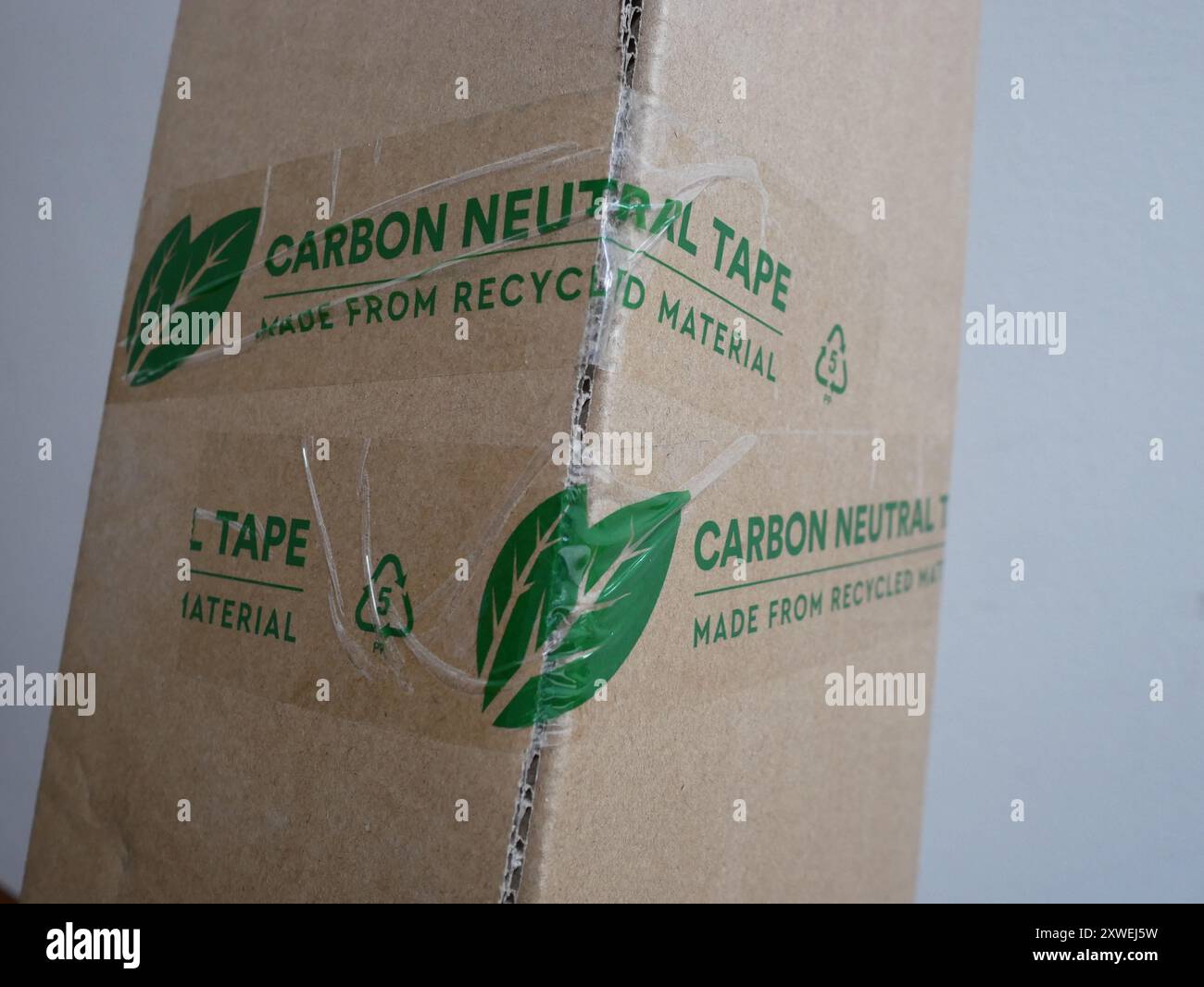 Imballaggio sostenibile con nastro neutro al carbonio realizzato in materiale riciclato che fissa una scatola di cartone. Foto Stock