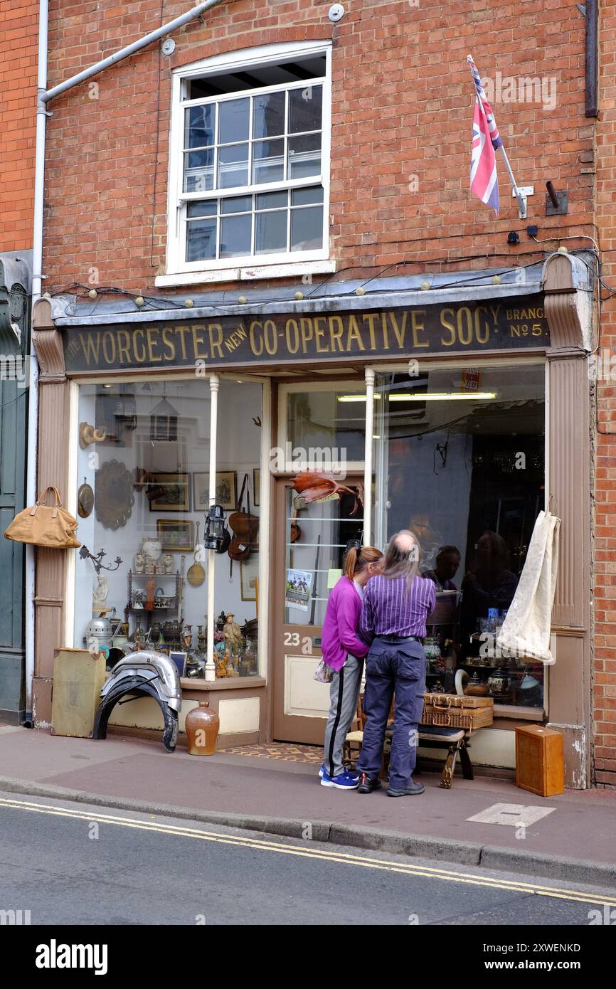 Una coppia che guarda in antiquariato, una vetrina di negozi di brac, Upton upon Severn, Worcestersire, Regno Unito Foto Stock