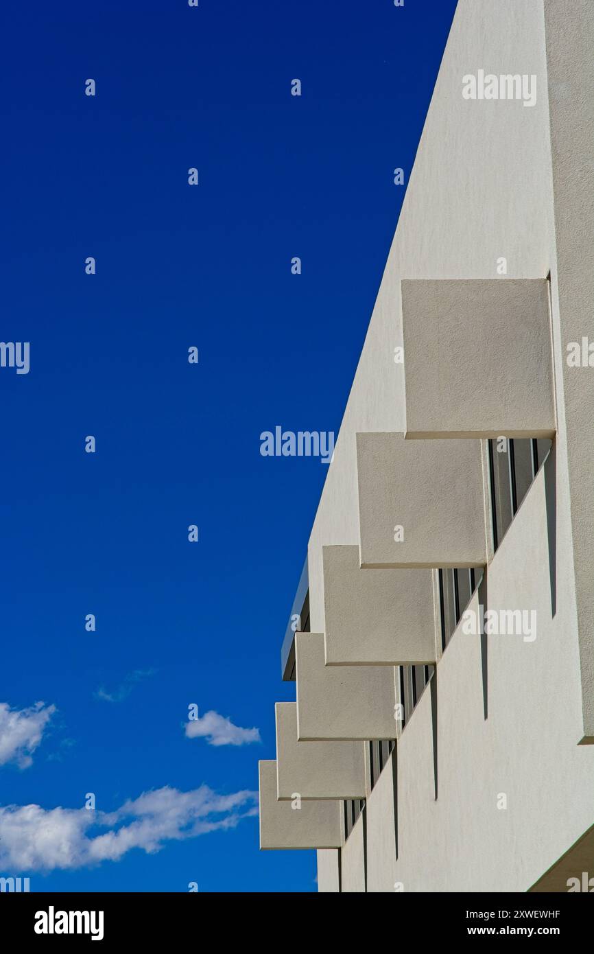 File di finestre con elementi ombreggianti verticali perpendicolari in un edificio contemporaneo in cemento Foto Stock