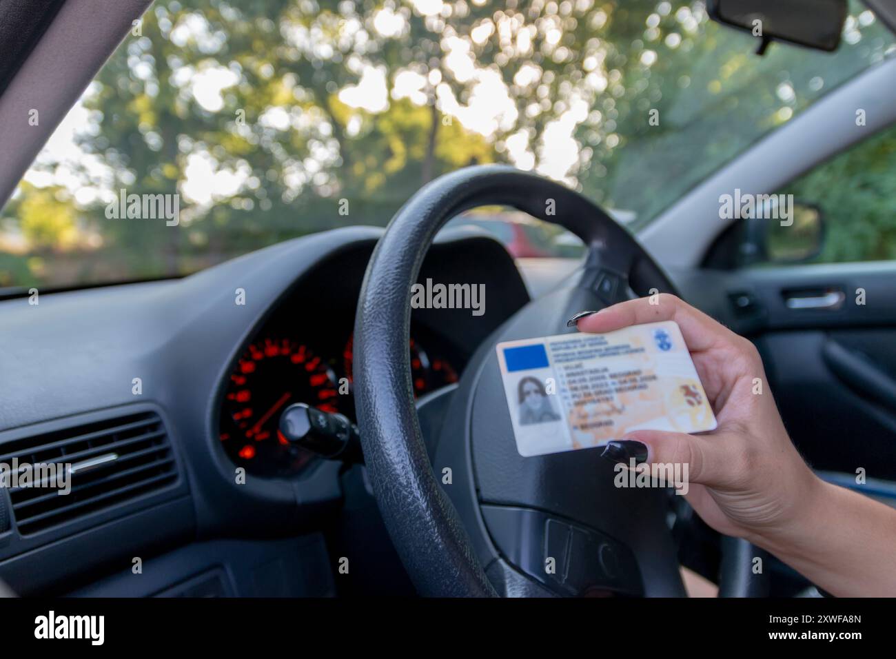 Adolescente che mostra la sua patente di guida nel finestrino dell'auto dopo aver superato l'esame o su richiesta della polizia stradale Foto Stock