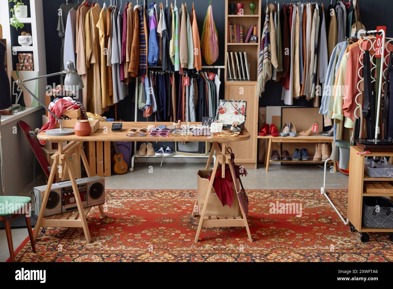 Foto di sfondo di un negozio thrift che vende capi di abbigliamento unici di seconda mano appesi al rack e accessori alla moda esposti sul tavolo, spazio per le copie Foto Stock