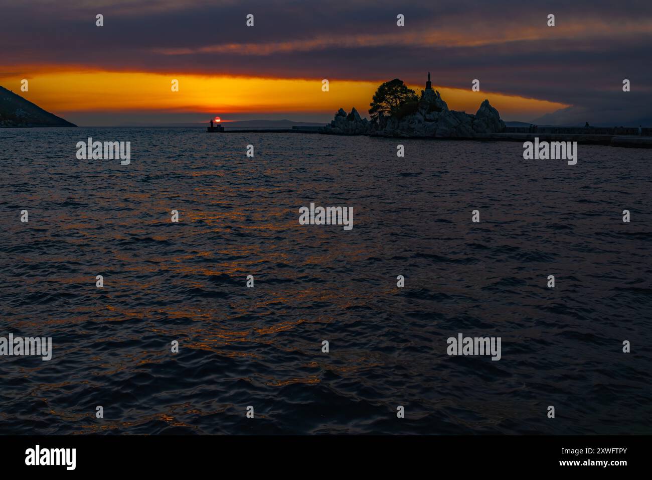 Il sole tramonta sotto l'orizzonte sul mare Adriatico in Croazia Foto Stock