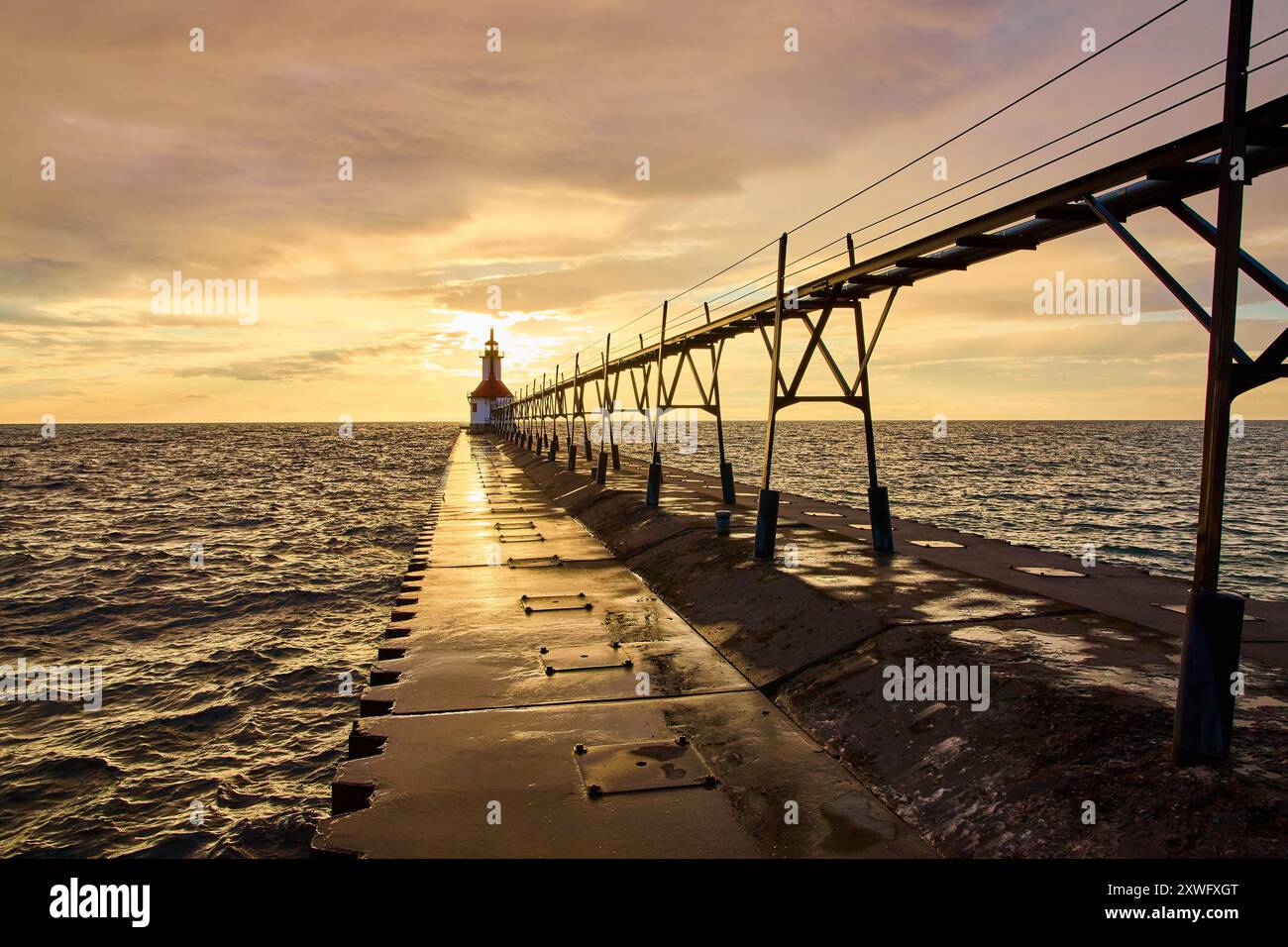 Faro al tramonto con Pier Reflection Low Eye-Level Perspective Foto Stock