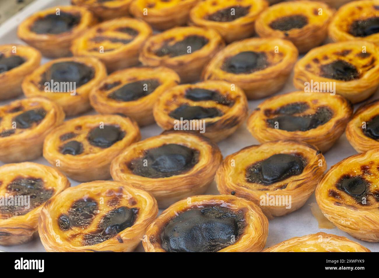 Pastel de nata (crostata crema) in vendita come si vede nella vetrina della pasticceria. La crostata alla crema pasticcera è la torta di pasticceria più famosa del Portogallo. Foto Stock