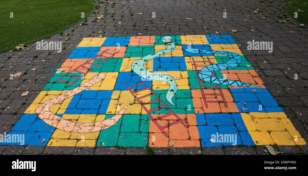 Colorato gioco da tavolo all'aperto Snakes and Ladders dipinto sul marciapiede in un parco. Calne, parco a comparsa, Wiltshire Foto Stock