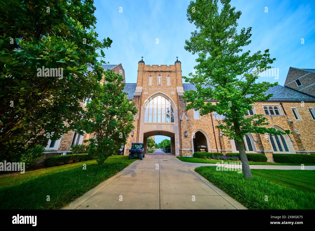 Edificio universitario in pietra gotica con ingresso ad arco e lussureggiante vegetazione a livello degli occhi Foto Stock