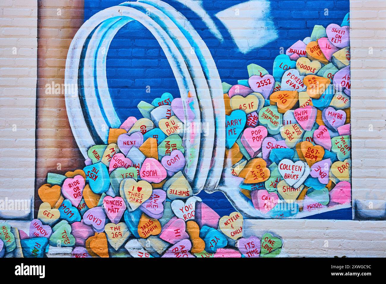 Murale Vibrant Candy Hearts sulla prospettiva a livello di occhi di mattoni Foto Stock
