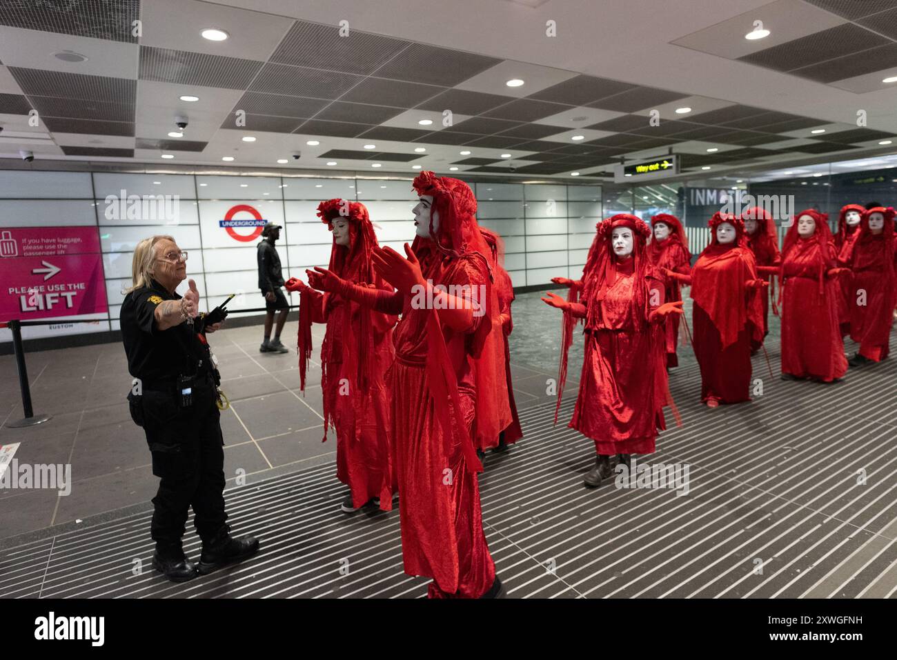 Londra, Regno Unito. 19 agosto 2024. La troupe di mimo attivista della ribellione rossa di Extinction Rebel si esibisce intorno alla stazione di Euston in una protesta silenziosa contro gli impatti ambientali del progetto ferroviario HS2, compresa la perdita di alberi e spazi verdi. Il progetto, il cui futuro è incerto, ha superato enormemente il budget e ha causato enormi sconvolgimenti nella zona, tra cui la perdita di case, imprese e l'esumazione di 50.000 resti umani. Crediti: Ron Fassbender/Alamy Live News Foto Stock