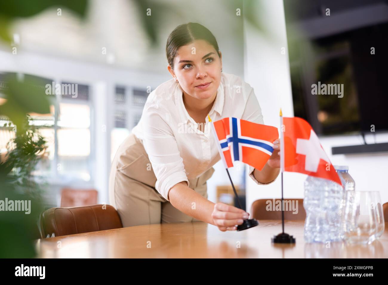Assistente donna prepara una sala conferenze per diplomatici di Svizzera e Norvegia Foto Stock