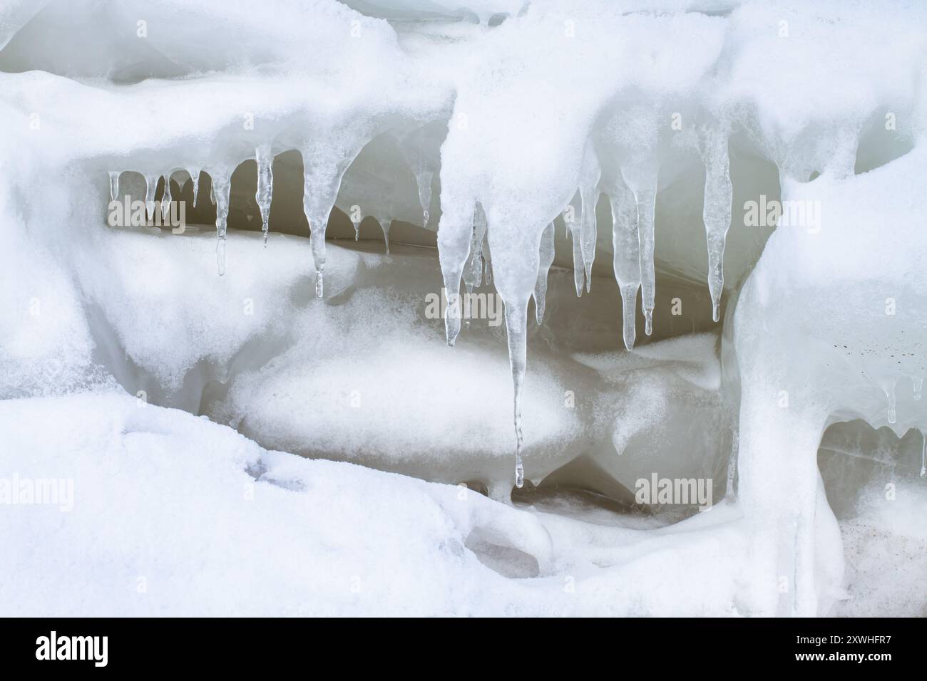 Un grande pavimento di ghiaccio è coperto di neve. Durante lo scongelamento, vi crebbero ghiaccioli di forma bizzarra. Foto Stock