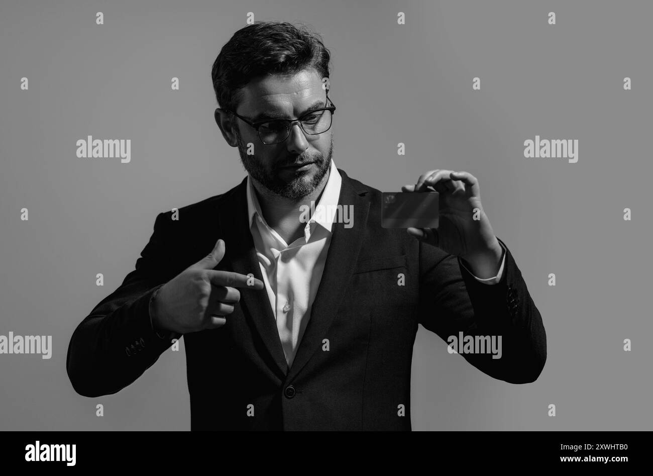Carta di credito. Millennial caucasico uomo d'affari di successo degli anni '40 con carta bancaria isolata su sfondo grigio, ritratto in studio. Lo stile di vita delle persone Foto Stock