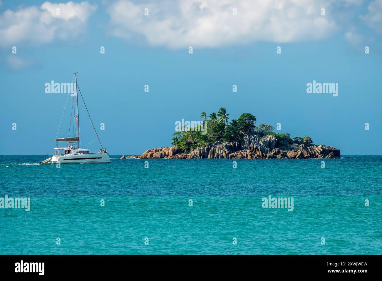Turisti a bordo di una barca a vela sull'isola di St Pierre, isoletta rocciosa panoramica nell'isola di Praslin, Seychelles Foto Stock