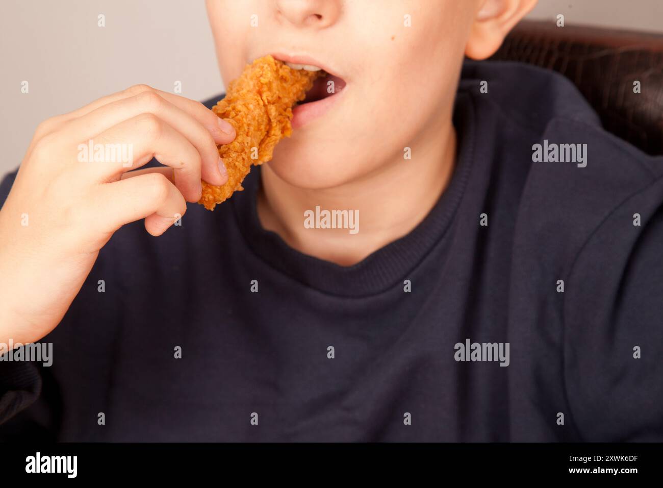 Uomo caucasico che mangia ali di pollo fritte dorate, cultura fast food americana, pezzi di ali di pollo cotti Foto Stock
