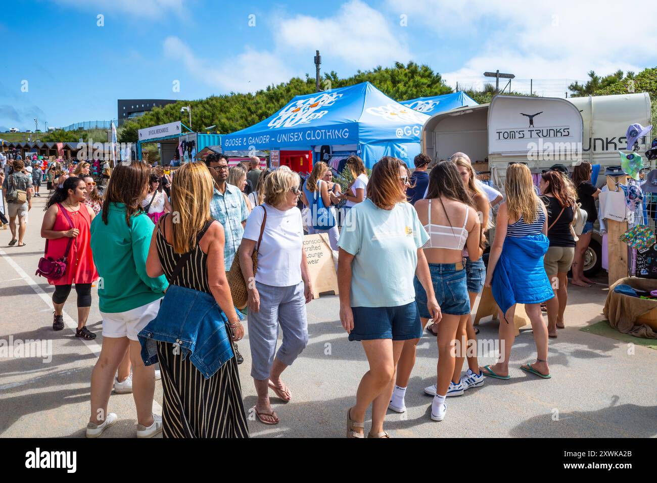 Turisti che navigano nel Surf Village al Boardmasters Surfing Festival al Fistral di Newquay in Cornovaglia nel Regno Unito. Foto Stock