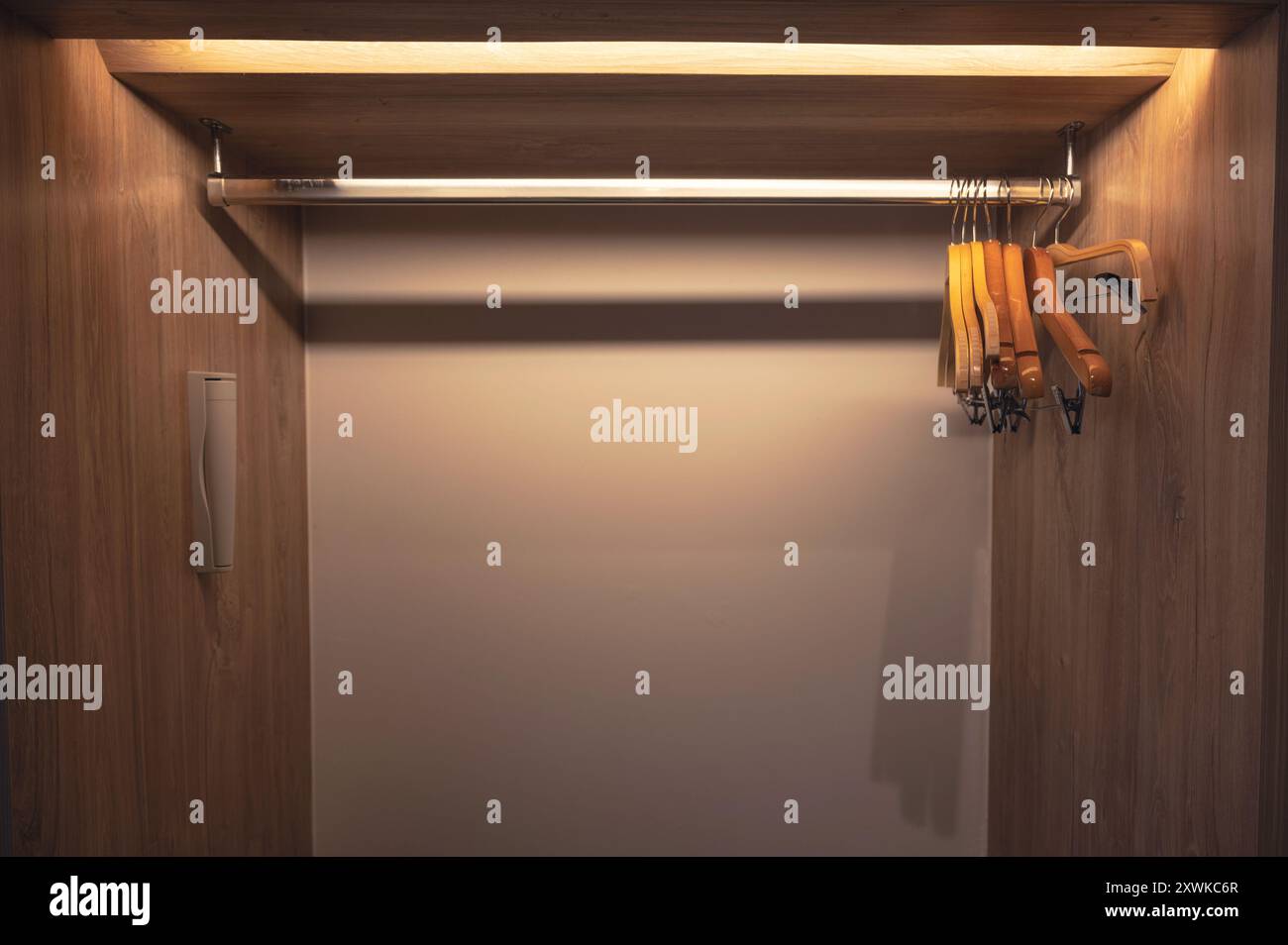 Fila di appendiabiti vuoti su guida in acciaio inox in legno armadio Foto Stock