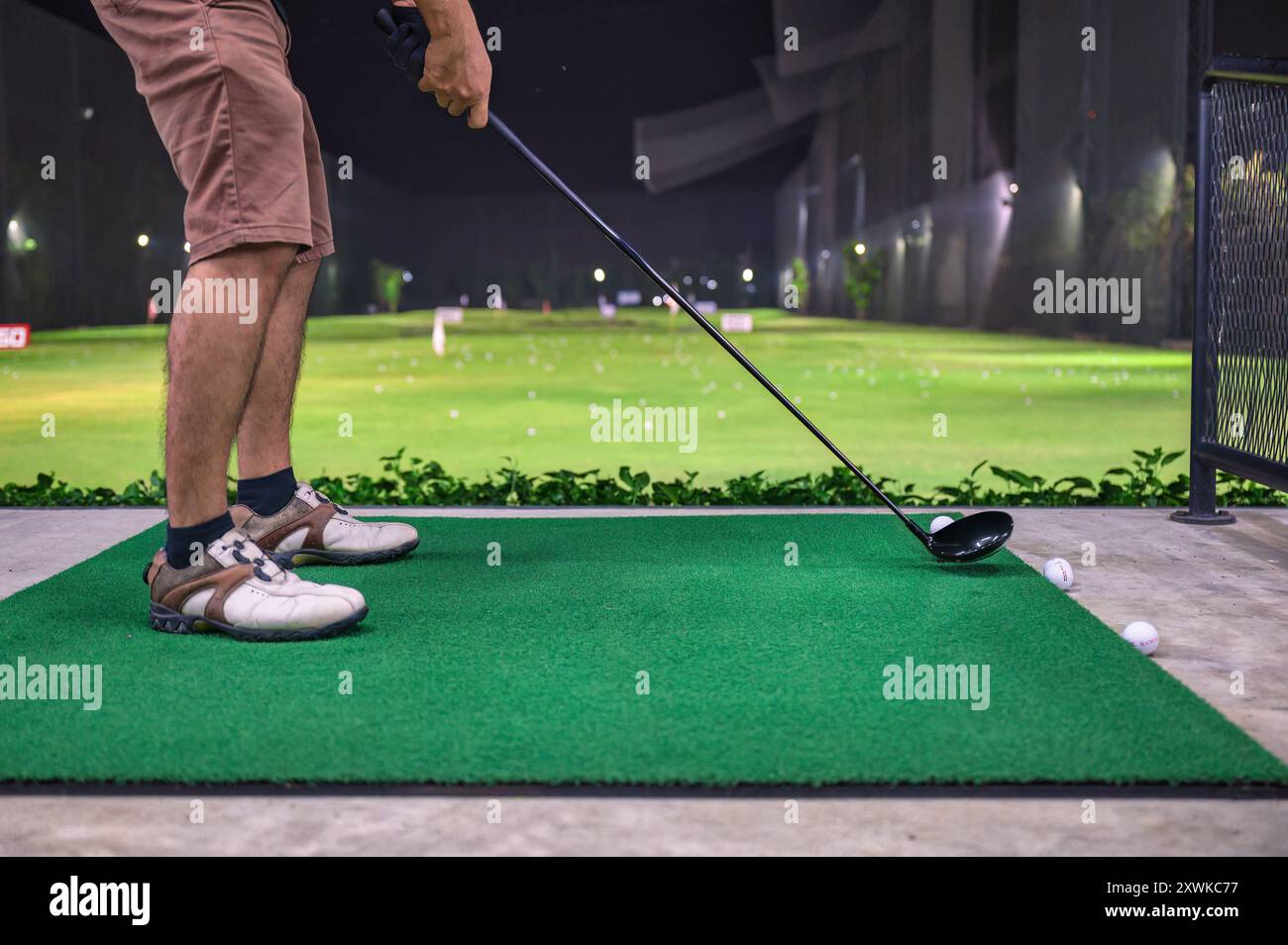 Un uomo che gioca e pratica con il golf swing sul campo da golf del campo pratica Foto Stock