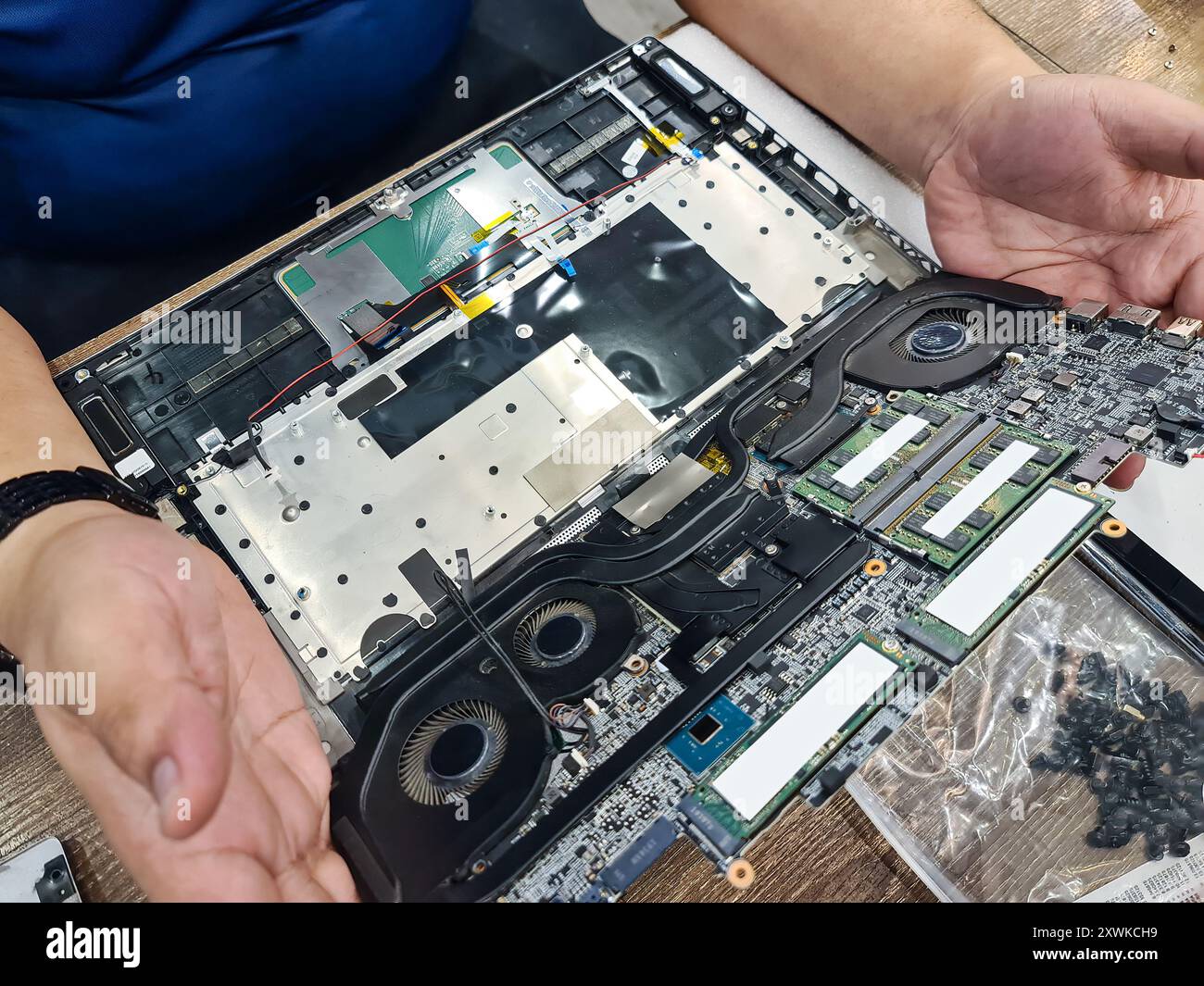 Tecnico informatico che smonta la scheda madre con il circuito di riparazione del laptop e aggiorna la tecnologia in officina Foto Stock