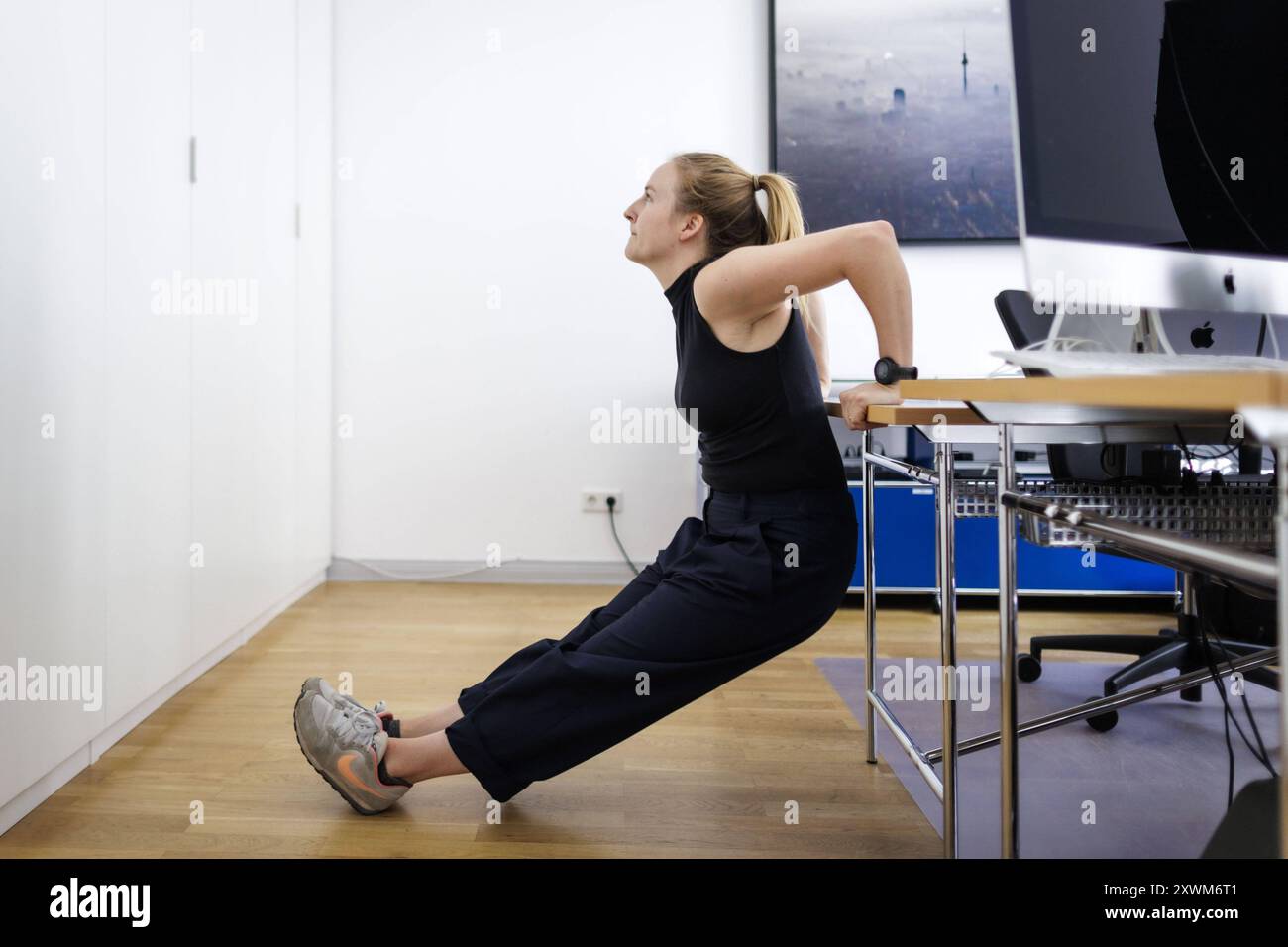 Eine Frau macht Sportuebungen am Arbeitsplatz in einem Buero a Berlino, 08.08.2024. Berlin Deutschland *** Una donna fa esercizi sportivi al lavoro in un ufficio a Berlino, 08 08 2024 Berlino Germania Copyright: XKiraxHofmann/photothek.dex Foto Stock