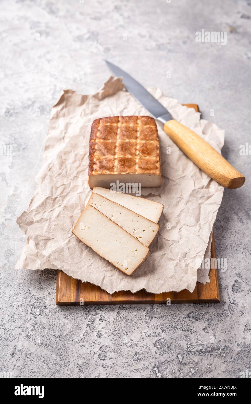 Tofu affumicato biologico sul tavolo della cucina con coltello Foto Stock