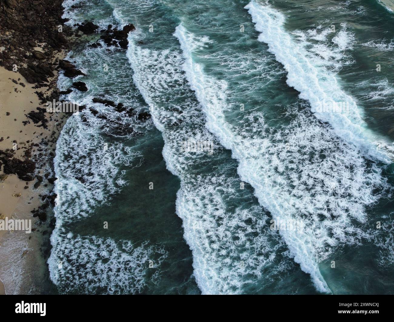 Onde che si infrangono con le rocce sulla spiaggia al tramonto di Koh Kradan Foto Stock