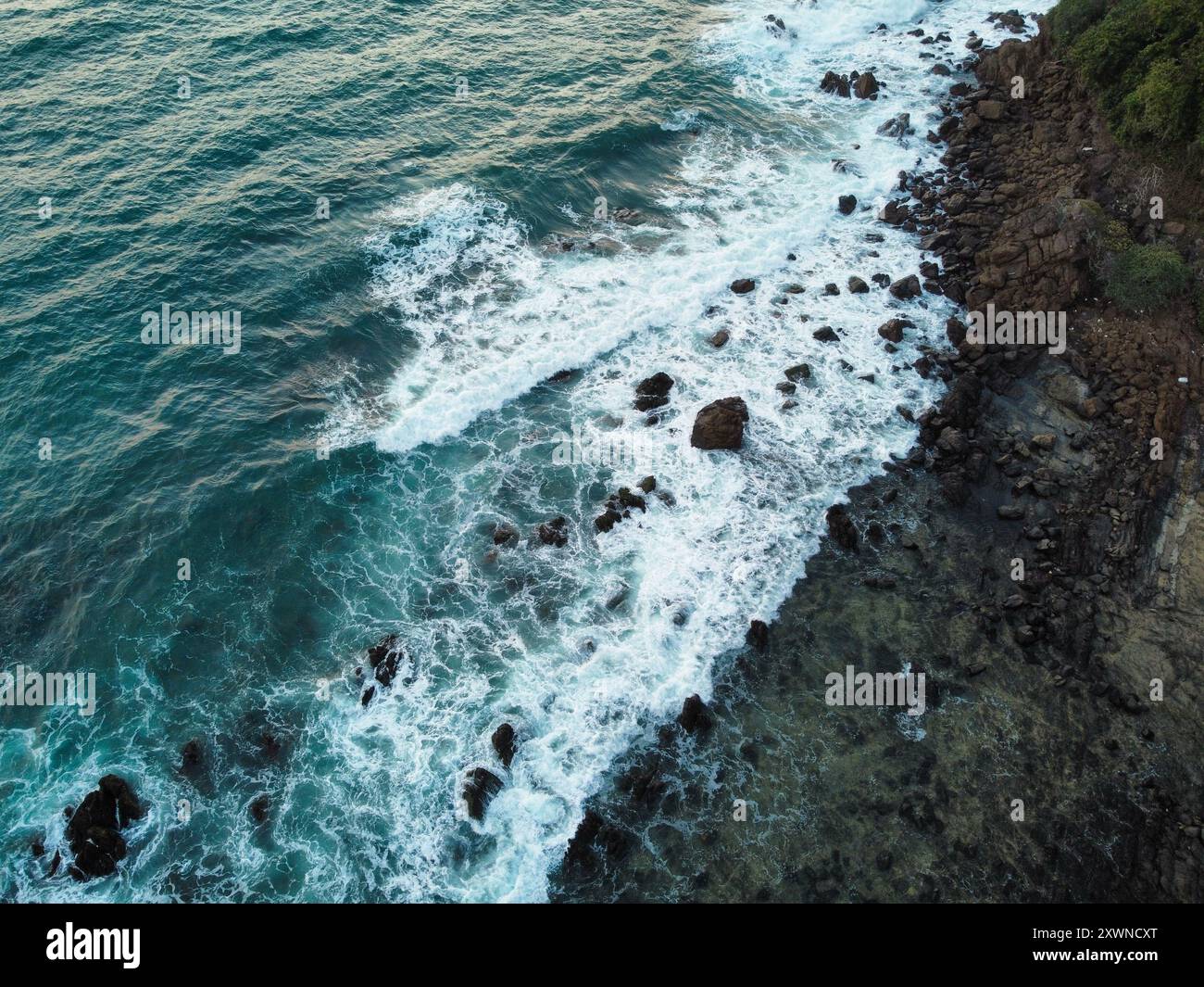 Onde che si infrangono con le rocce sulla spiaggia al tramonto di Koh Kradan Foto Stock