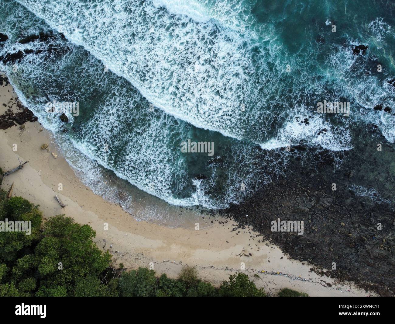 Onde che si infrangono con le rocce sulla spiaggia al tramonto di Koh Kradan Foto Stock