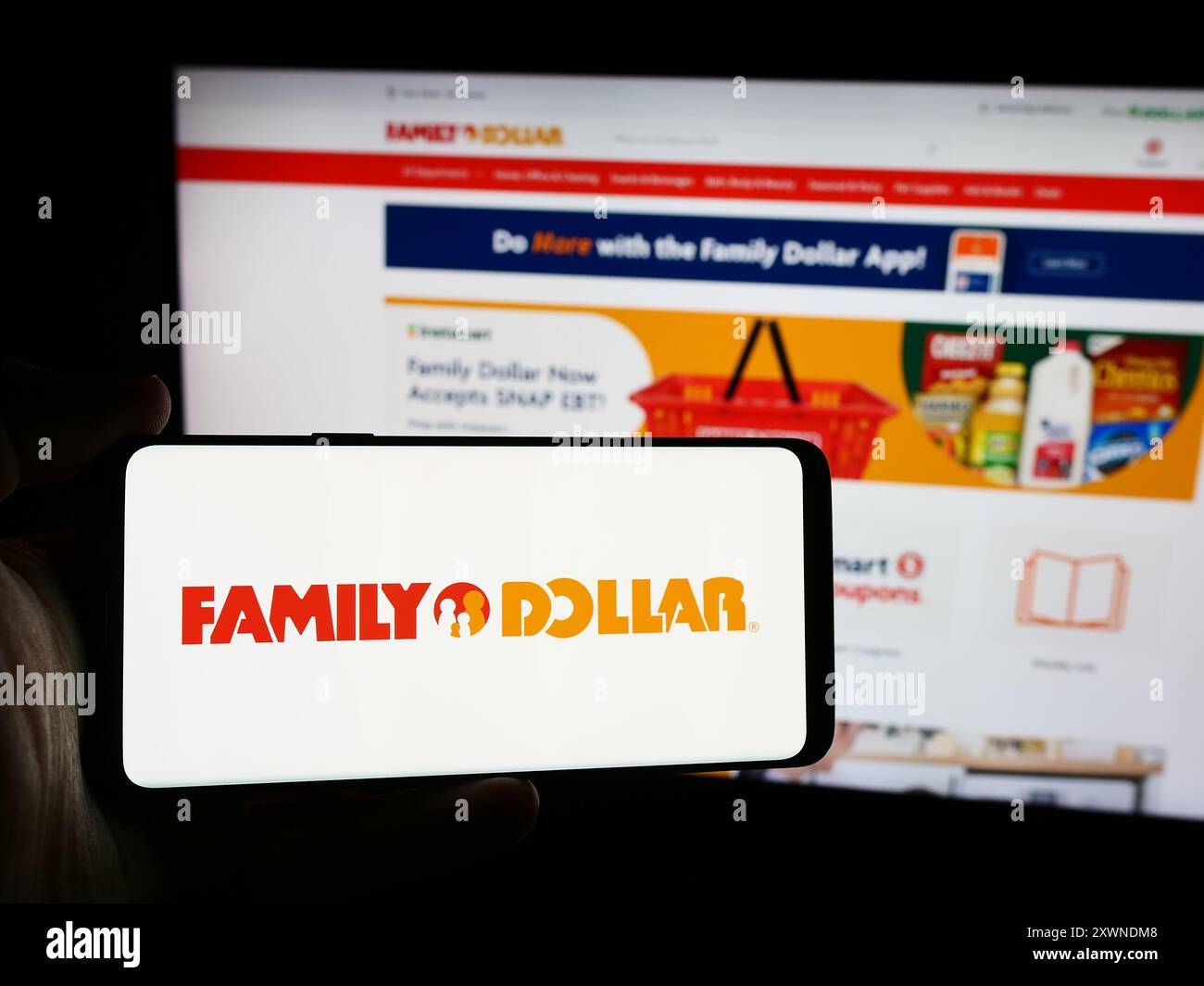 Persona con smartphone con logo della società statunitense Family Dollar Stores Inc. Davanti al sito Web. Mettere a fuoco il display del telefono. Foto Stock