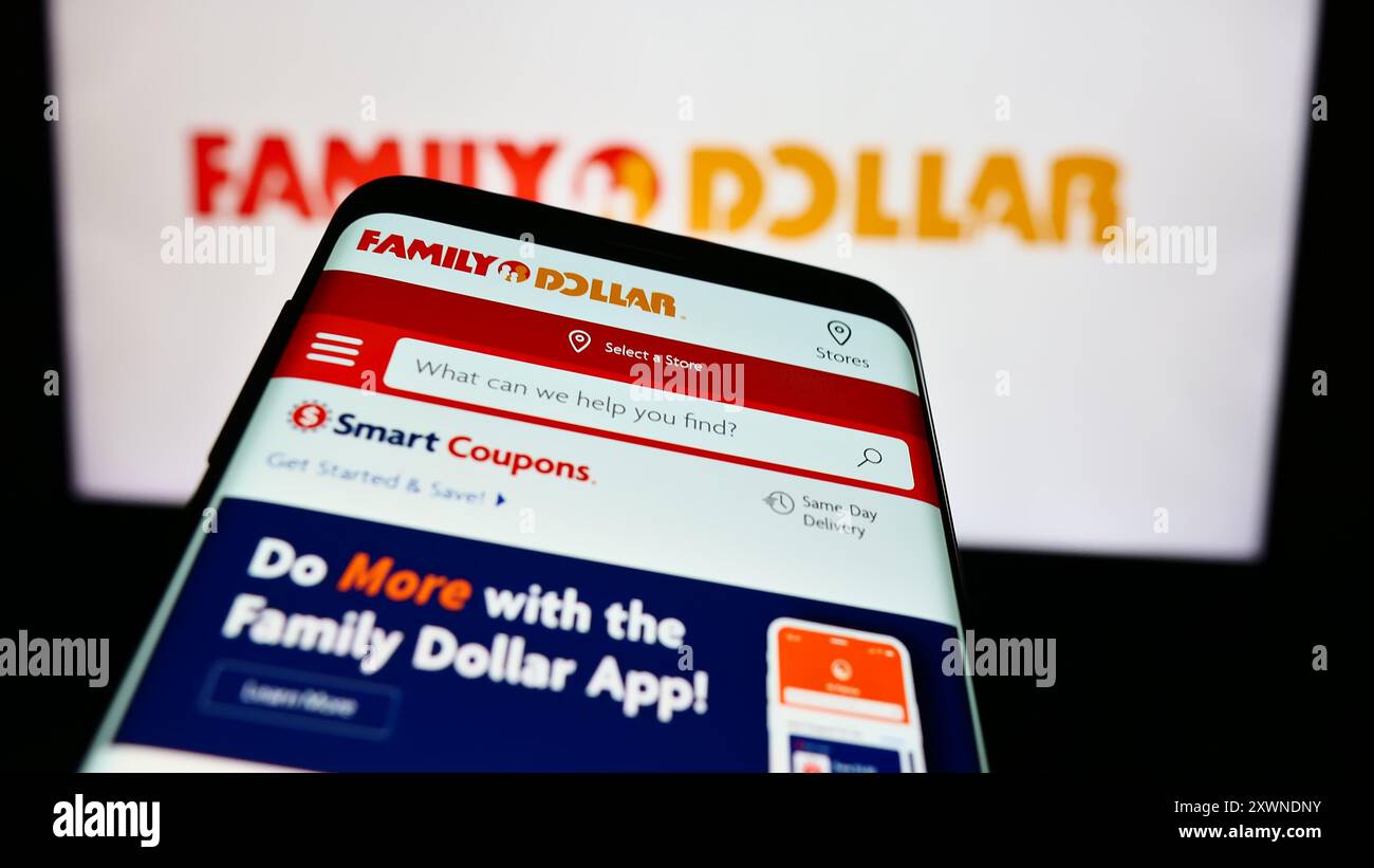 Smartphone con sito Web della società statunitense Family Dollar Stores Inc. Davanti al logo aziendale. Mettere a fuoco in alto a sinistra sul display del telefono. Foto Stock