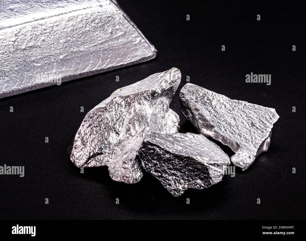 lingotto o barra di alluminio accanto al minerale di alluminio, al riciclaggio o al concetto di industria dei metalli Foto Stock