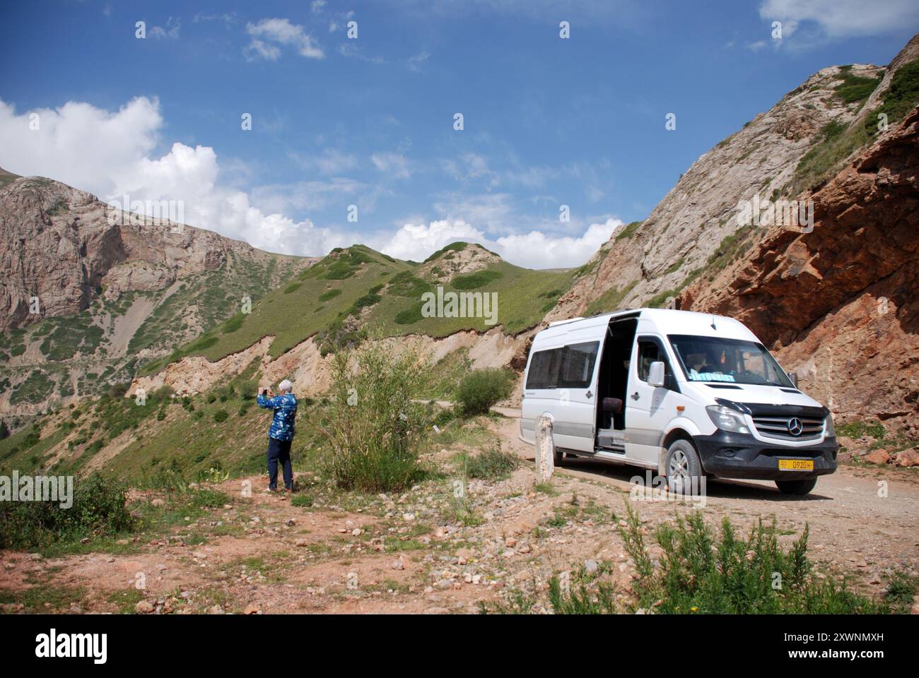 Un minibus Mercedes parcheggiato sul lato della strada nel paesaggio montano del Kirghizistan Foto Stock