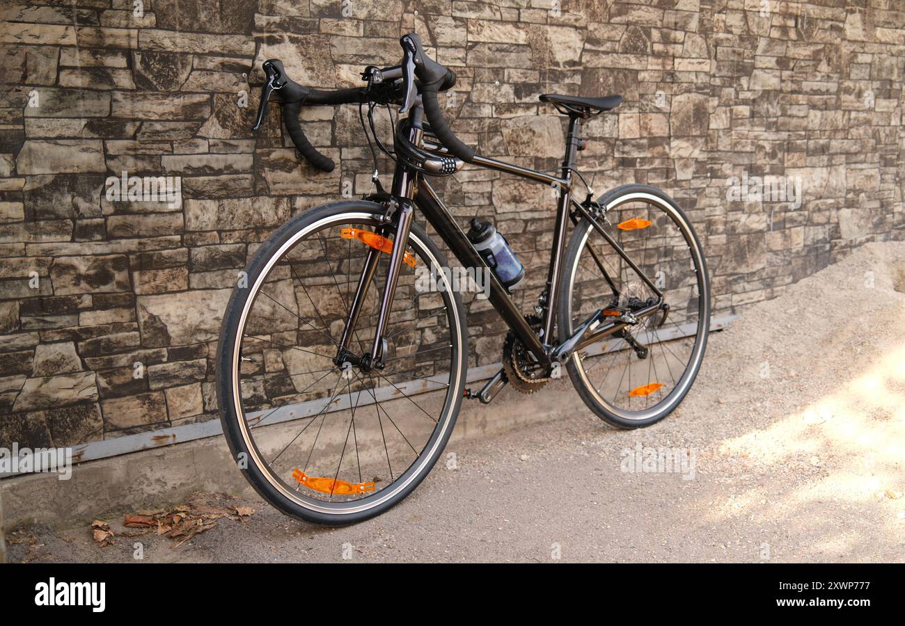 Bicicletta da corsa appoggiata contro un muro di pietra. Bici da strada parcheggiata sul marciapiede. Concetto di ciclismo urbano e trasporto ecologico Foto Stock