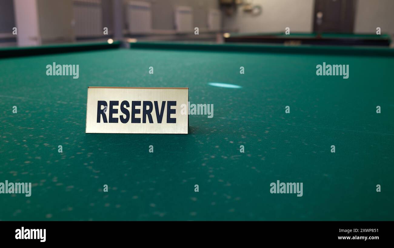 Cartello di riserva sul tavolo da biliardo verde. Giochi esclusivi, area VIP nella sala piscina o nel club, concetto di industria dell'intrattenimento Foto Stock