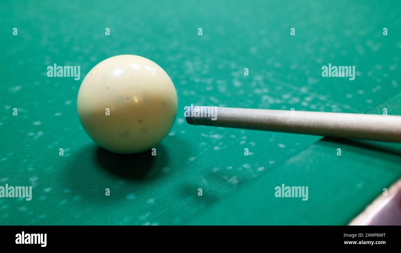 Il giocatore che punta il bersaglio si attacca alla palla bianca sul tavolo da biliardo. Primo piano di una partita da biliardo in azione, sport e attività ricreative Foto Stock
