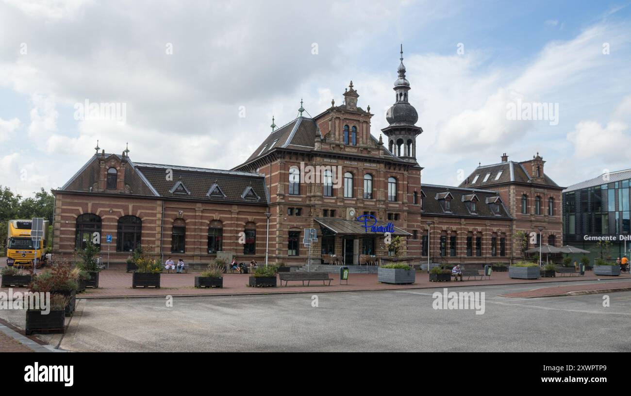 DELFT, OLANDA MERIDIONALE, PAESI BASSI - 26 LUGLIO 2024: Veduta della piazza della stazione con l'ex stazione ferroviaria di Delft. L'edificio è attualmente in Foto Stock