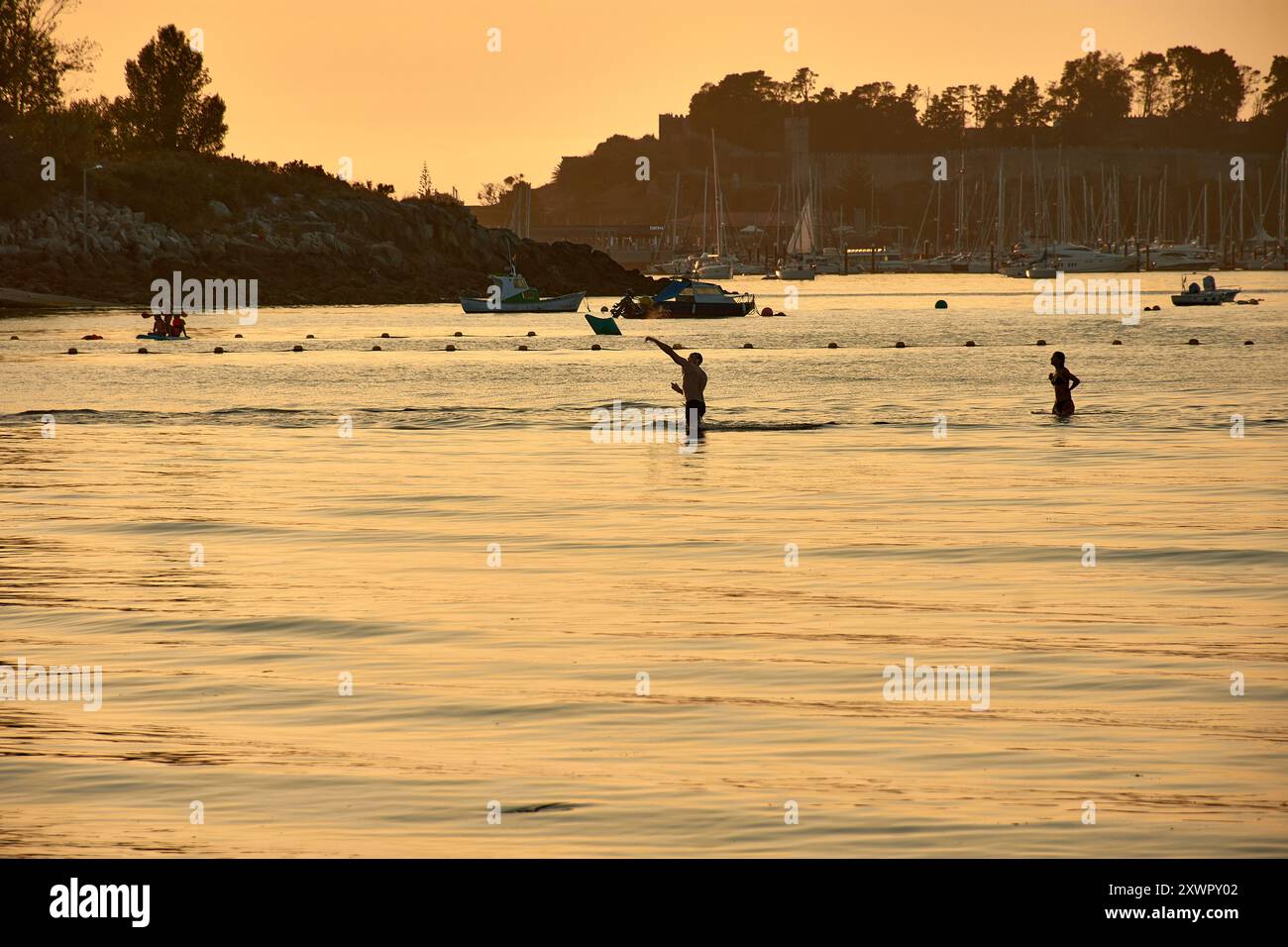 Mentre il giorno sbiadisce nella notte, le sagome dei giovani che giocano e fanno il bagno nelle acque di Ladeira Beach creano un'affascinante e nostalgica sce Foto Stock