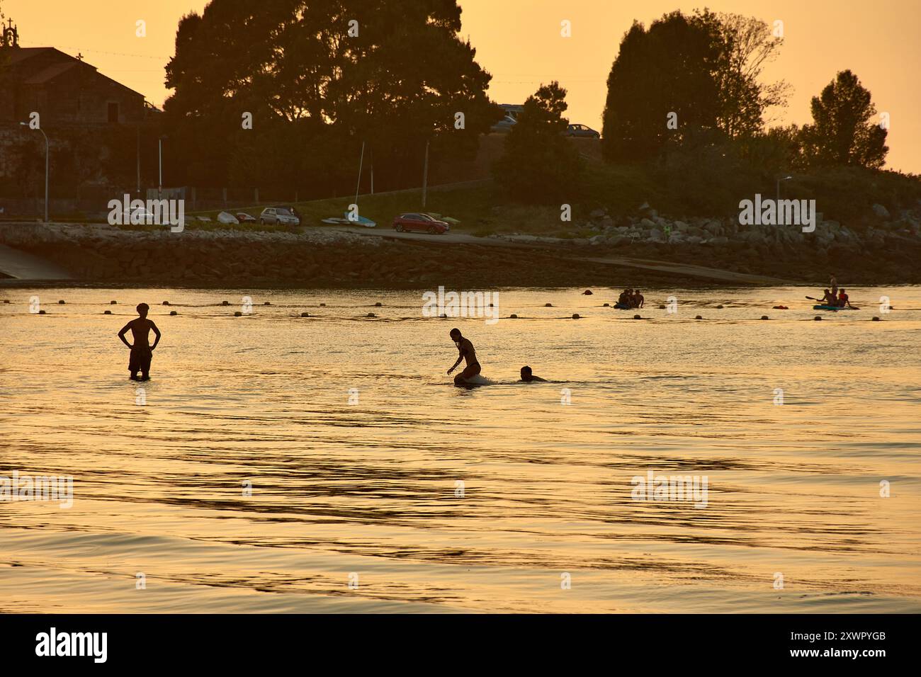 Mentre il giorno sbiadisce nella notte, le sagome dei giovani che giocano e fanno il bagno nelle acque di Ladeira Beach creano un'affascinante e nostalgica sce Foto Stock