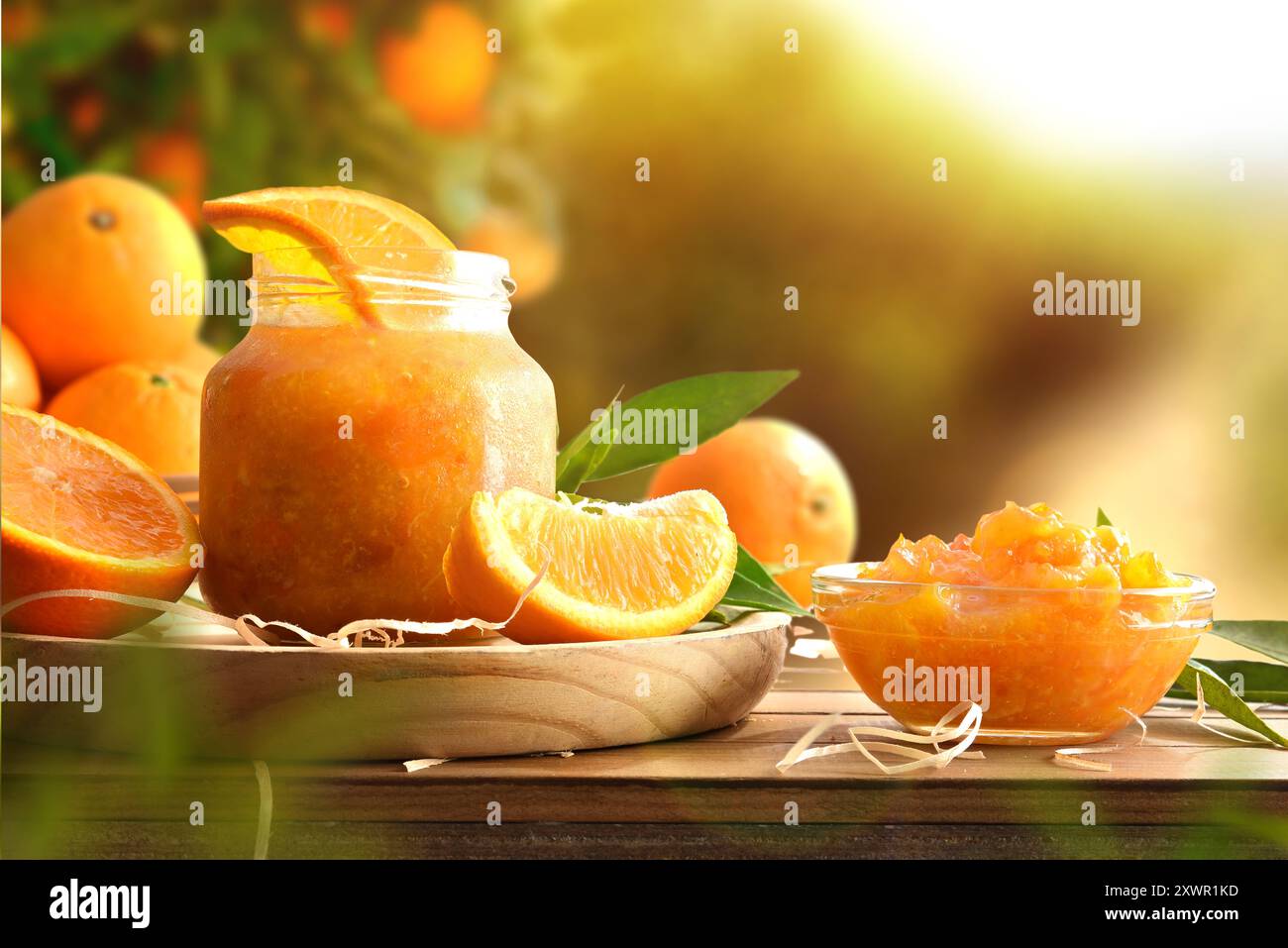 Marmellata d'arancia fatta in casa in vasetti di vetro su tavola di legno e sfondo naturale. Vista frontale. Foto Stock