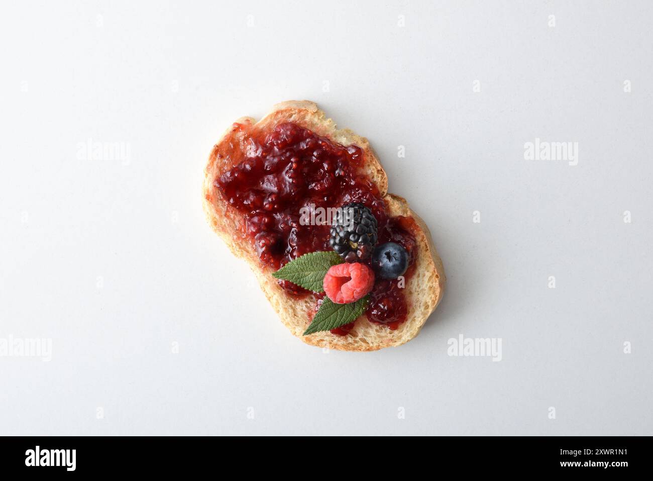 Toast con marmellata di frutta della foresta decorata con frutta isolata su un tavolo bianco. Vista dall'alto. Foto Stock