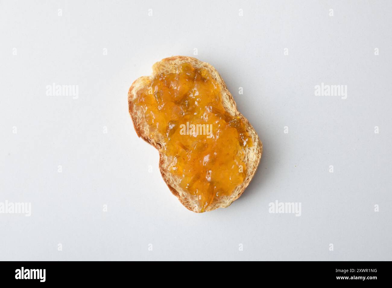 Toast con marmellata di prugne decorata con frutta isolata su un tavolo bianco. Vista dall'alto. Foto Stock