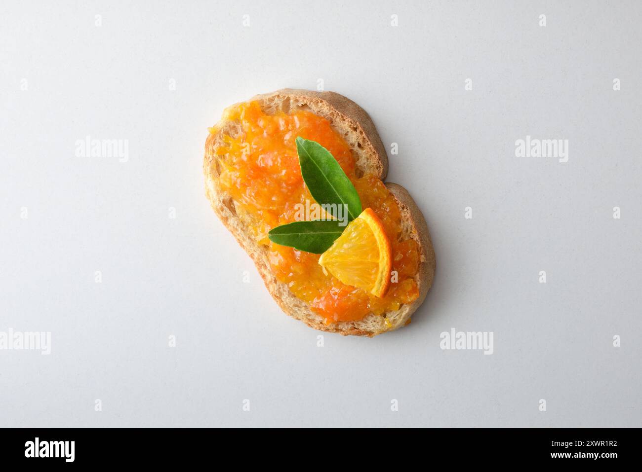Toast con marmellata d'arancia decorata con frutta isolata su un tavolo bianco. Vista dall'alto. Foto Stock