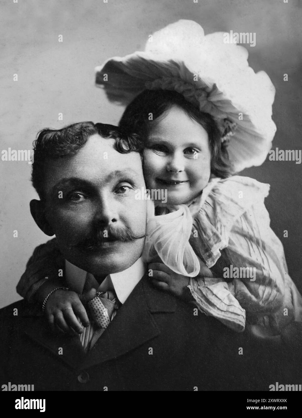 Una ragazza incredibilmente carina abbraccia suo padre con un sorriso, CA. 1895. Foto Stock