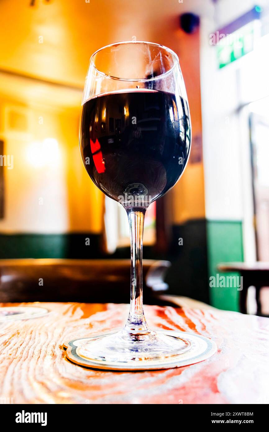 primo piano di un bicchiere di vino rosso su un tavolo di legno nell'accogliente pub britannico Foto Stock