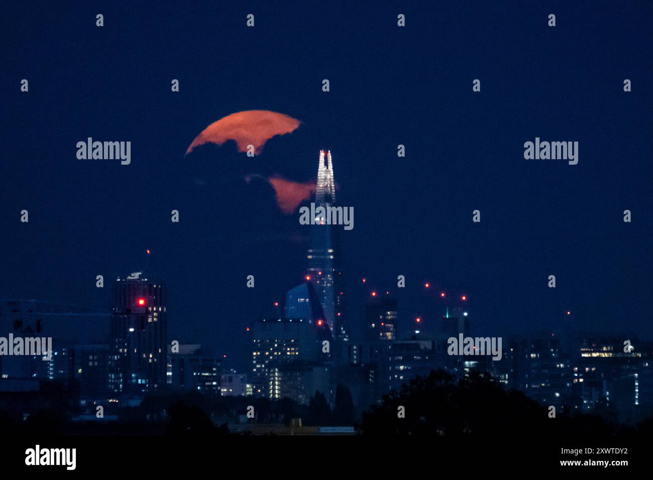 Londra, Regno Unito. 20 agosto 2024. Meteo nel Regno Unito – Una luna gibbosa in calo del 99% sorge dietro lo Shard e lo skyline della capitale, il giorno dopo la luna piena di agosto. Conosciuta come la Luna di Sturgeon secondo l'Almanacco dell'Old Farmer a causa del gran numero di pesci storione che sono stati trovati nei grandi Laghi in Nord America in questo periodo dell'anno, la luna piena di agosto è anche conosciuta come una "superluna blu" che appare più luminosa e più grande in quanto sarà nel punto più vicino alla Terra nella sua orbita. Crediti: Stephen Chung / Alamy Live News Foto Stock