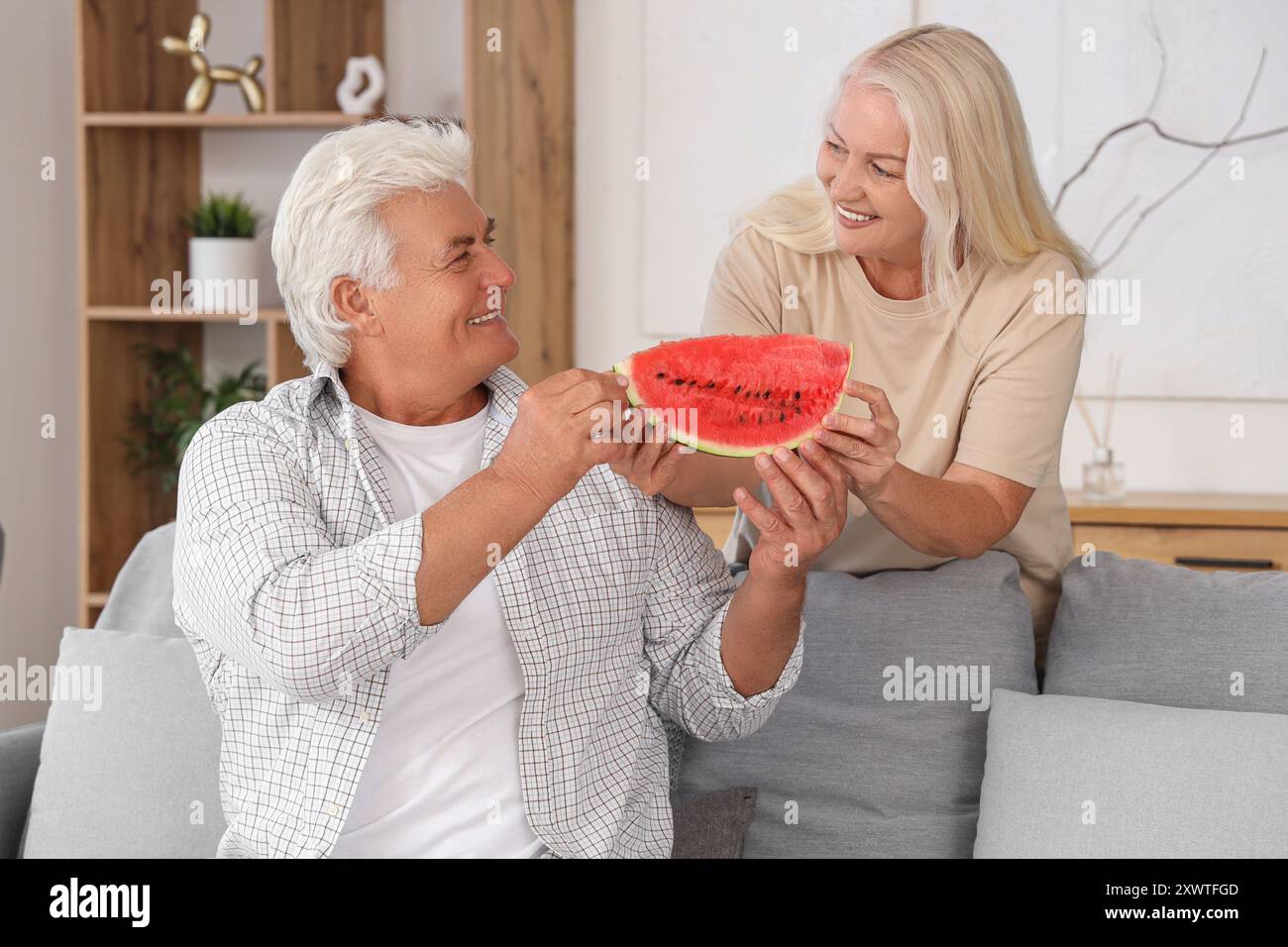 Coppia matura con una fetta di anguria a casa Foto Stock