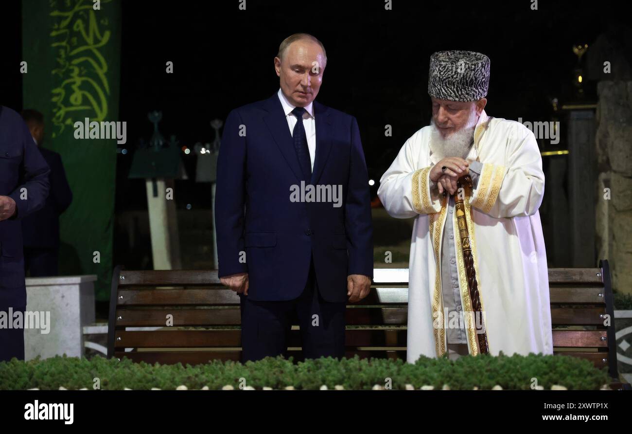 Akhmat-Yurt, Russia. 20 agosto 2024. Il presidente russo Vladimir Putin, a sinistra, parla con Khozh-Akhmed Kadyrov, presidente del Consiglio di alim ceceno e cugino di Akhmat Kadyrov, primo presidente della Repubblica cecena, durante una visita al cimitero, il 20 agosto 2024, a Akhmat-Yurt, distretto di Kurchaloyevsky, Repubblica cecena, Russia. Crediti: Vyacheslav Prokofyev/piscina del Cremlino/Alamy Live News Foto Stock