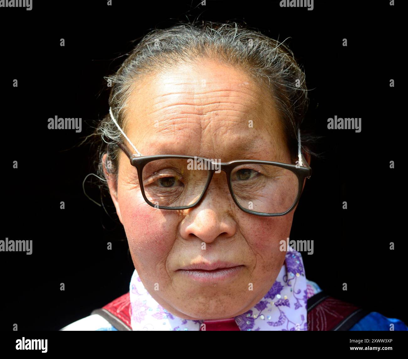 Ritratto di una donna Miao Long Horn che indossa occhiali divertenti. Guizhou, Cina. Foto Stock